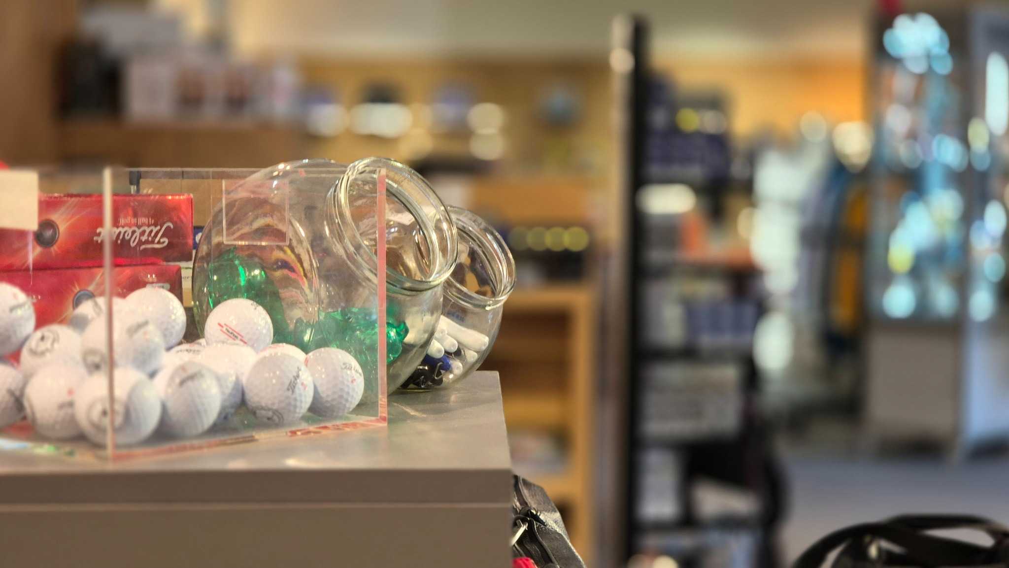 Golfbälle, Tees und Golfzubehör auf einem Verkaufstresen in einem Golfshop